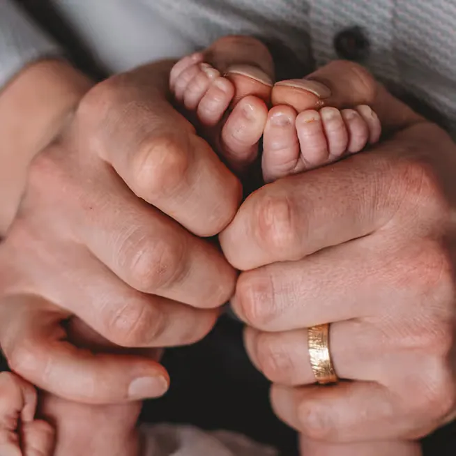 Babyvoetjes in de handen van de ouders met trouwring