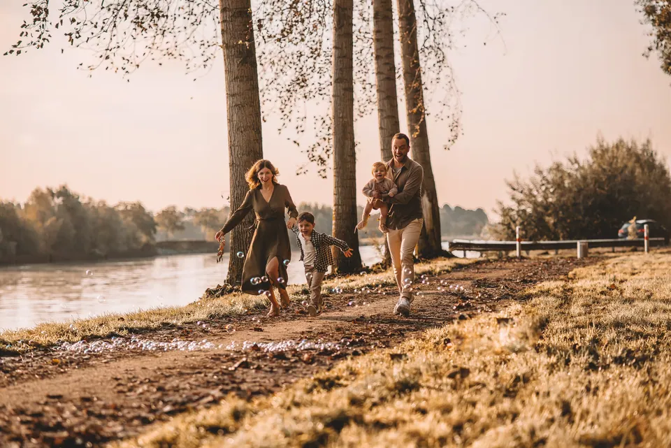 Gezin wandelt langs de rivier tussen hoge bomen
