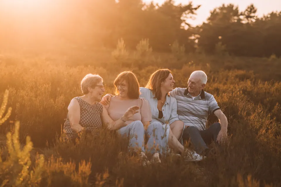 Familie zit samen in de heide bij zonsondergang