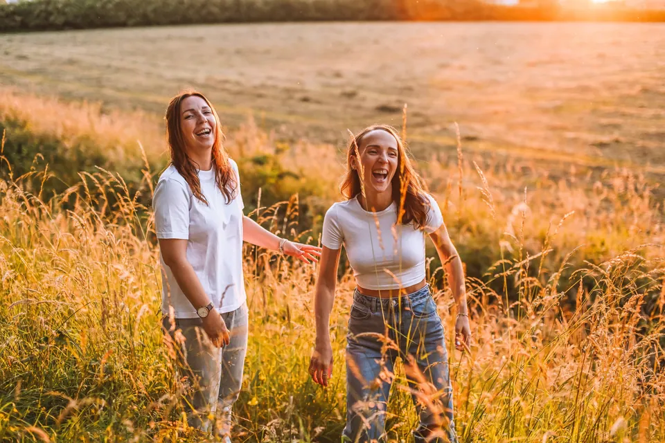 Twee zussen zitten in een veld vol hoog gras