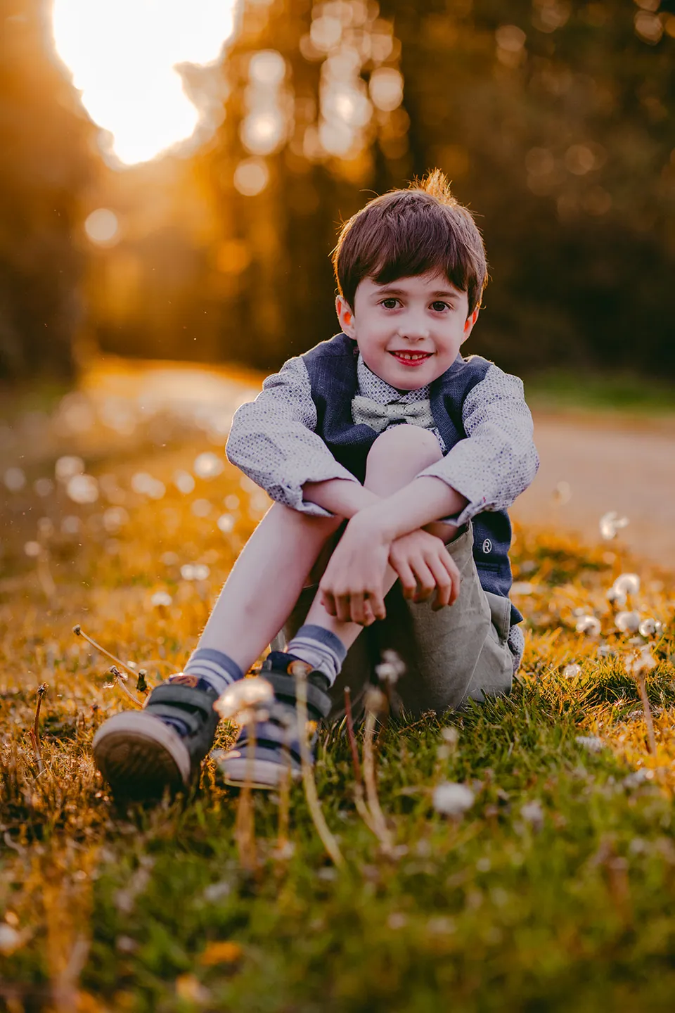 Communicant zit in het gras terwijl de zon door de bomen valt