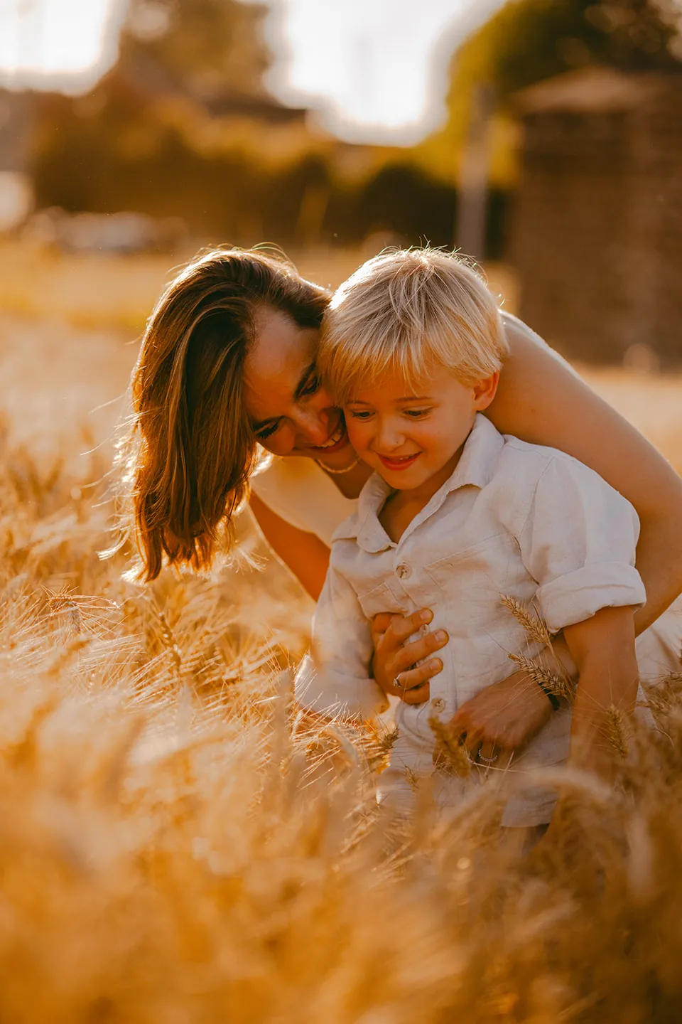 Mama en zoon knuffelen in een goudgeel korenveld