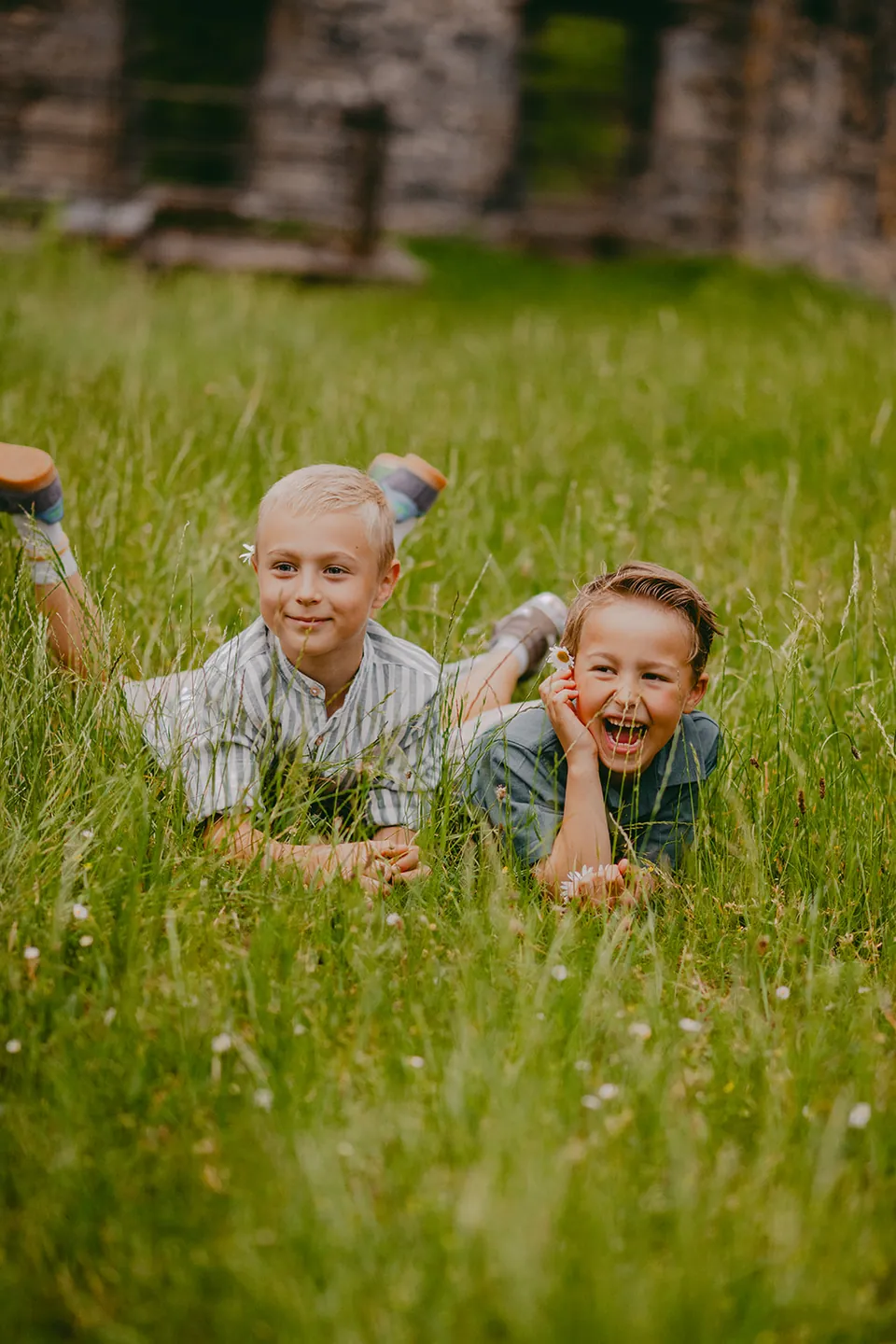 Twee broers liggen lachend in het hoge gras