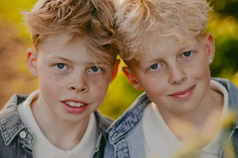 Twee broers met sproeten, wang aan wang in de zon