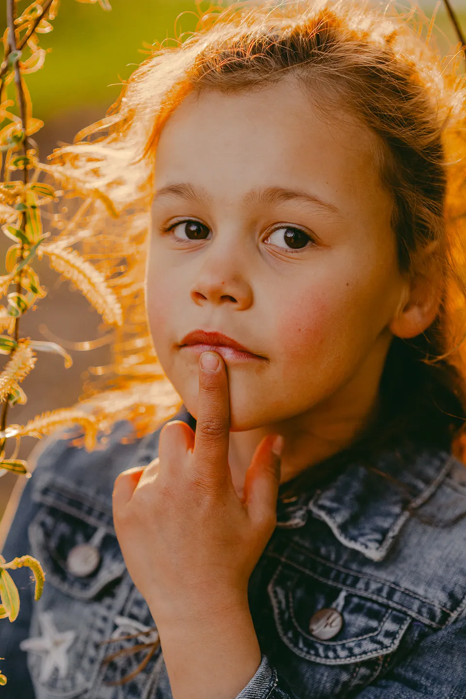 Meisje in tegenlicht met haar vinger nadenkend op haar kin