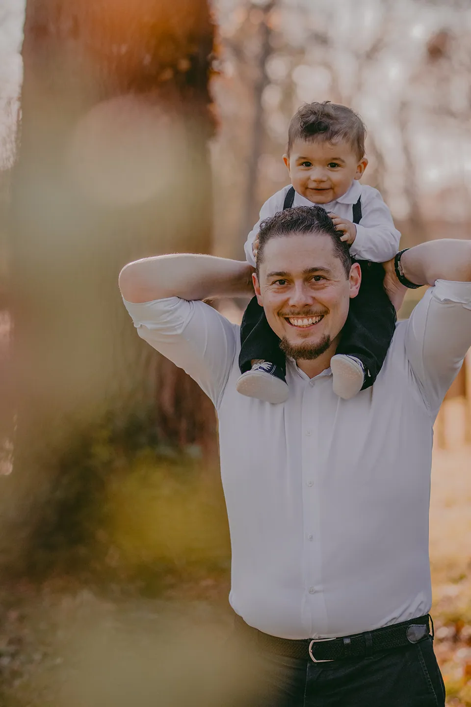 Baby op de schouders van papa tussen warme herfstkleuren