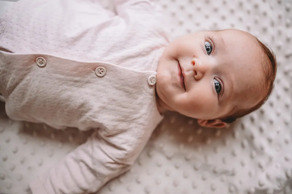 Baby ligt lachend op een zacht dekentje
