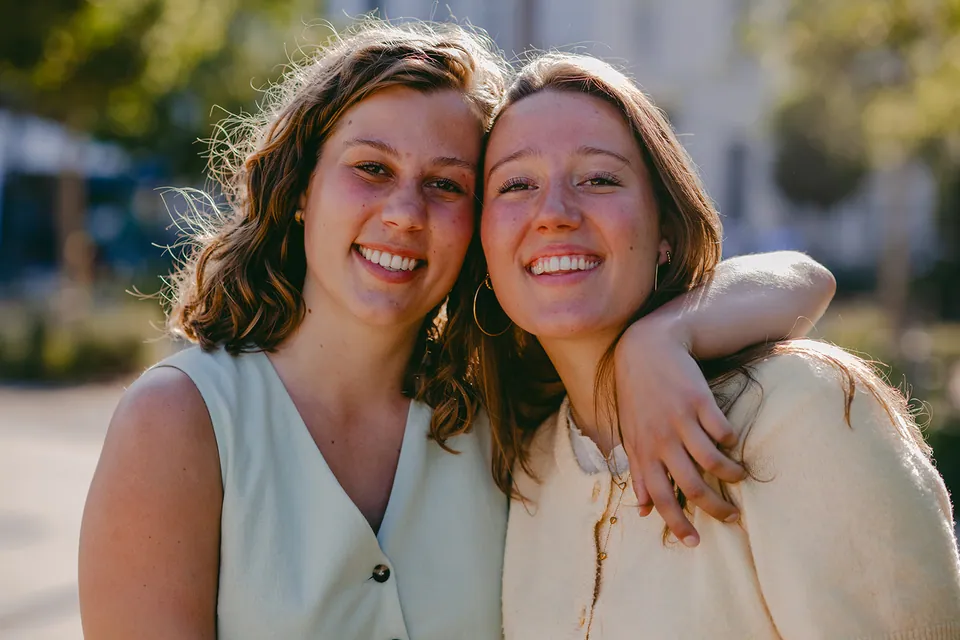Twee meiden lachen wang aan wang in de late zon