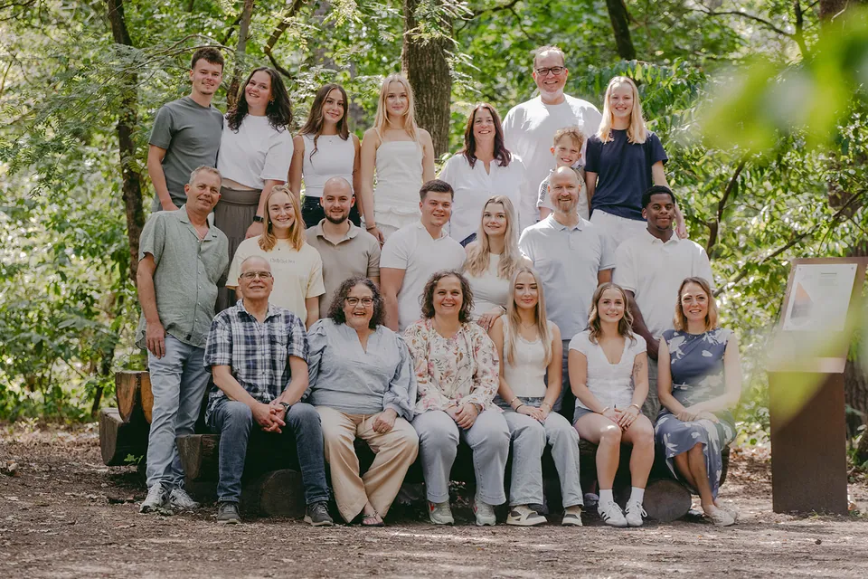 Een familie van drie generaties, meer dan twintig personen, samen op een bank in het bos